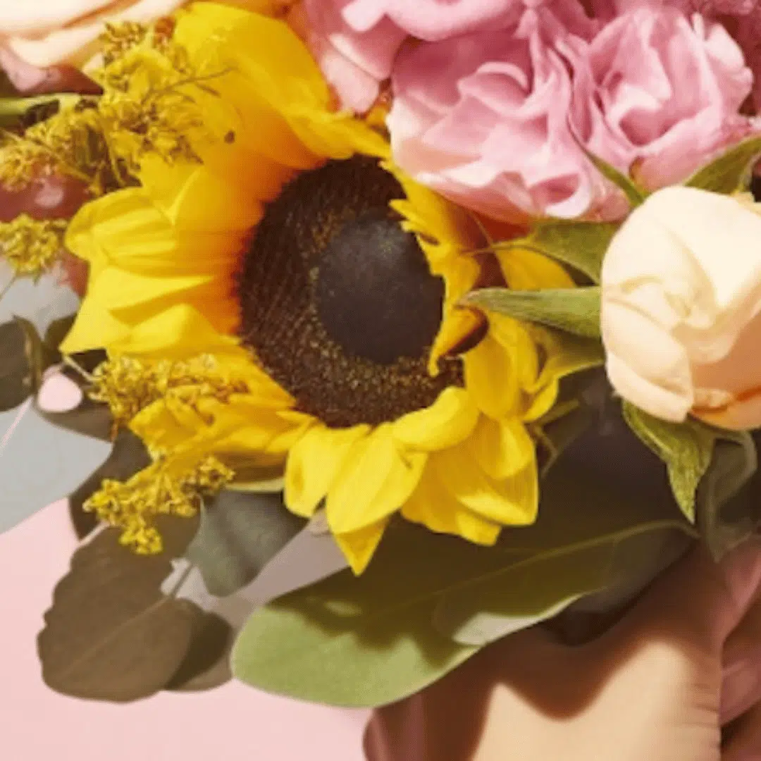 close up of a sunflower and pastel colour roses bouquet